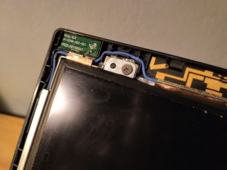 Jeden ze šroubků, které drží na místě displej notebooku.